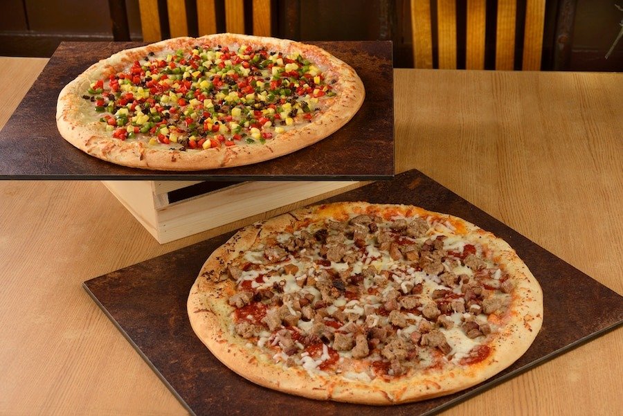 two pizzas on stands on a wood table